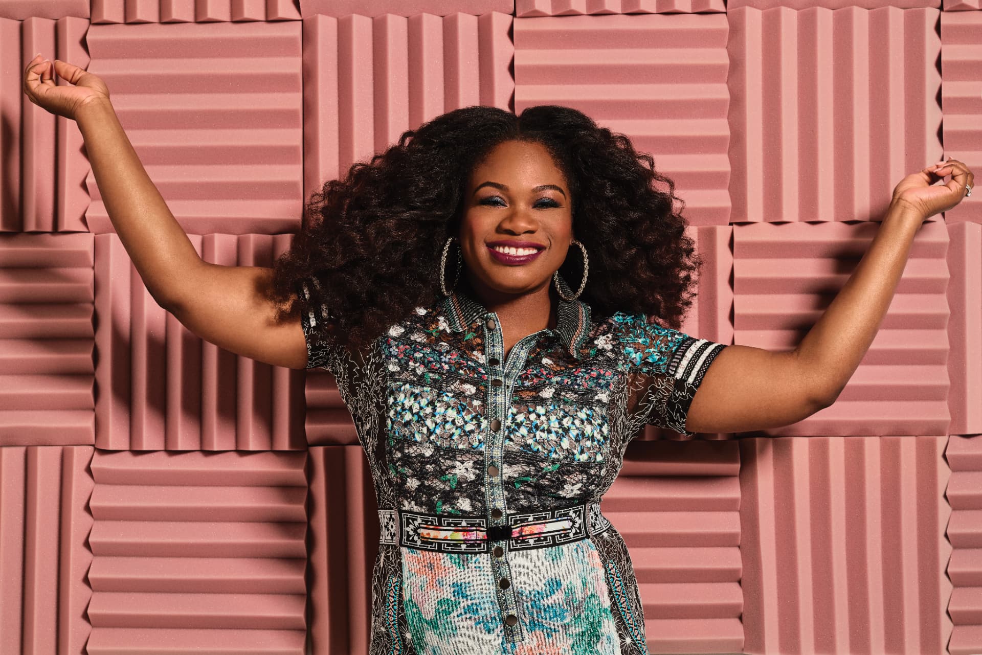Nicaila Matthews Okome with arms raised in a podcast studio